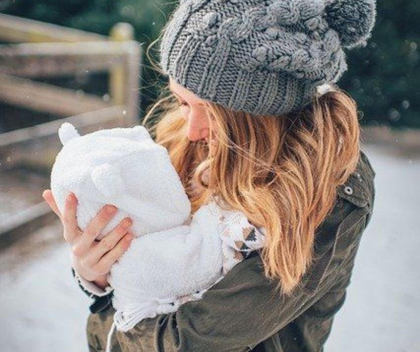 Mom holding baby in snow suit best winter gear for baby