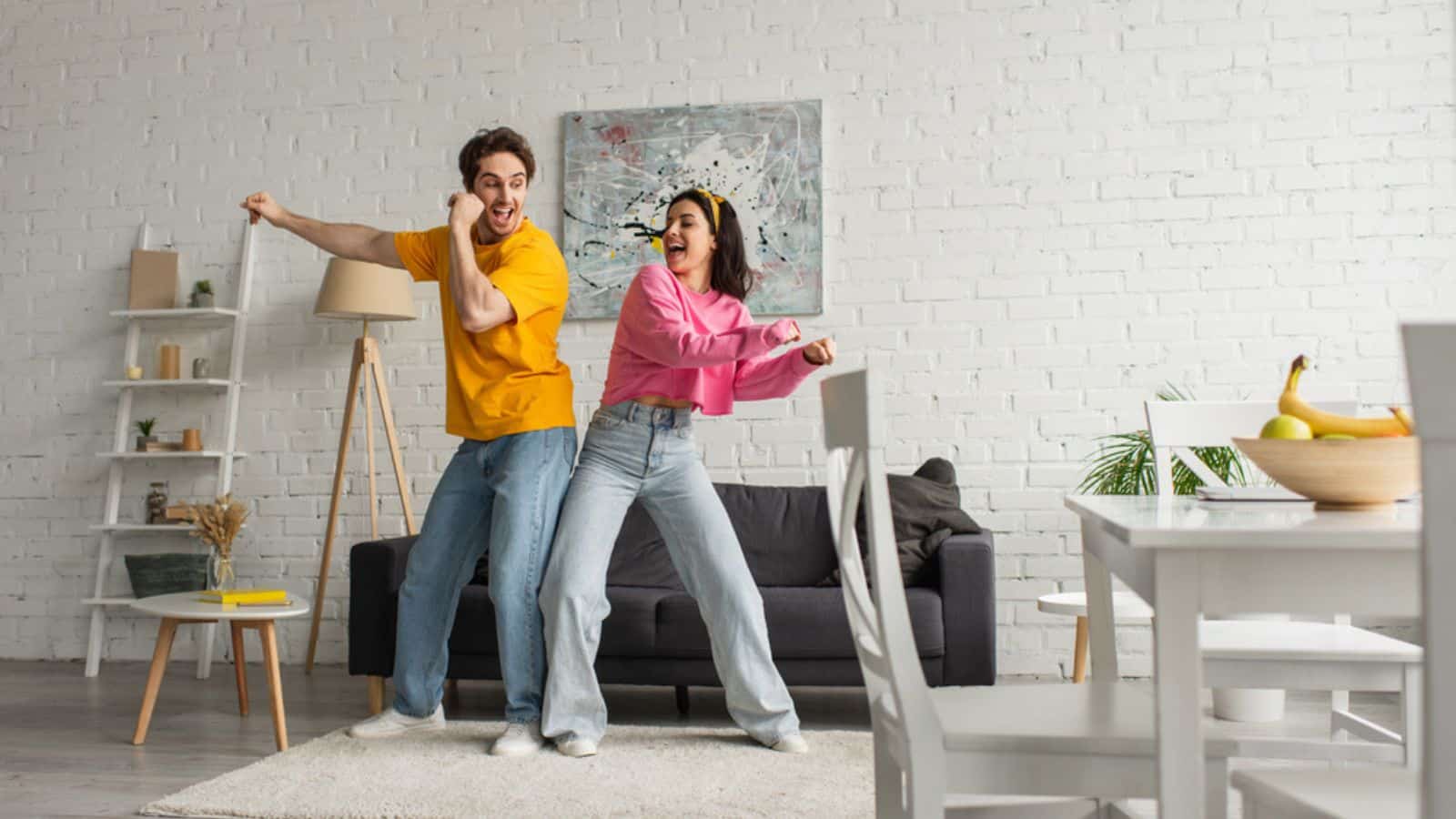 Smiling young couple in casual clothes dancing in modern loft.jpg